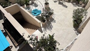 Una terrazza sul tetto con posti a sedere, una scala a chiocciola e piante in vaso.