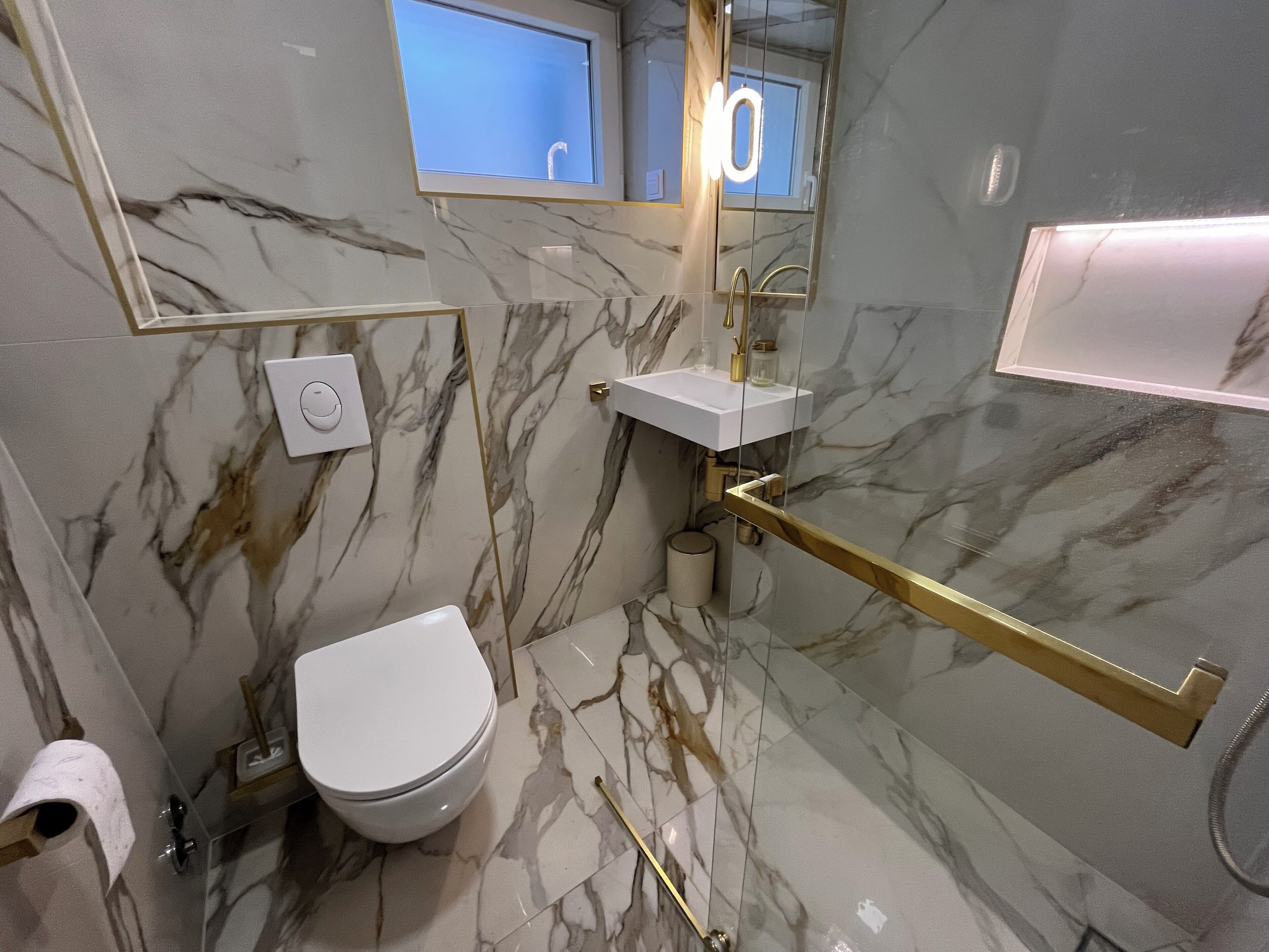 Ein modernes Badezimmer mit Toilette, Waschbecken und einer Duschkabine aus Glas.