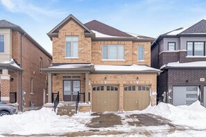 A residential building with a brick facade, two garage doors, and a snow-covered roof. - Modern Luxury 5 ⭐ Space near Brampton | Sleeps 8 (caledon)
