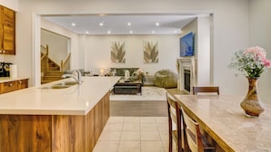 A modern kitchen with a central island, a dining area with a marble table, and a living room with a sofa and a fireplace. - Modern Luxury 5 ⭐ Space in Caledon| Sleeps 8 (caledon)
