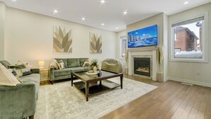 A living room with a sofa set, a coffee table, a fireplace, and a TV mounted on the wall. - Modern Luxury 5 ⭐ Space in Caledon| Sleeps 8 (caledon)