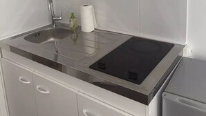 Eine Küche mit Spülbecken aus Edelstahl, integriertem Kochfeld und weißen Schränken.