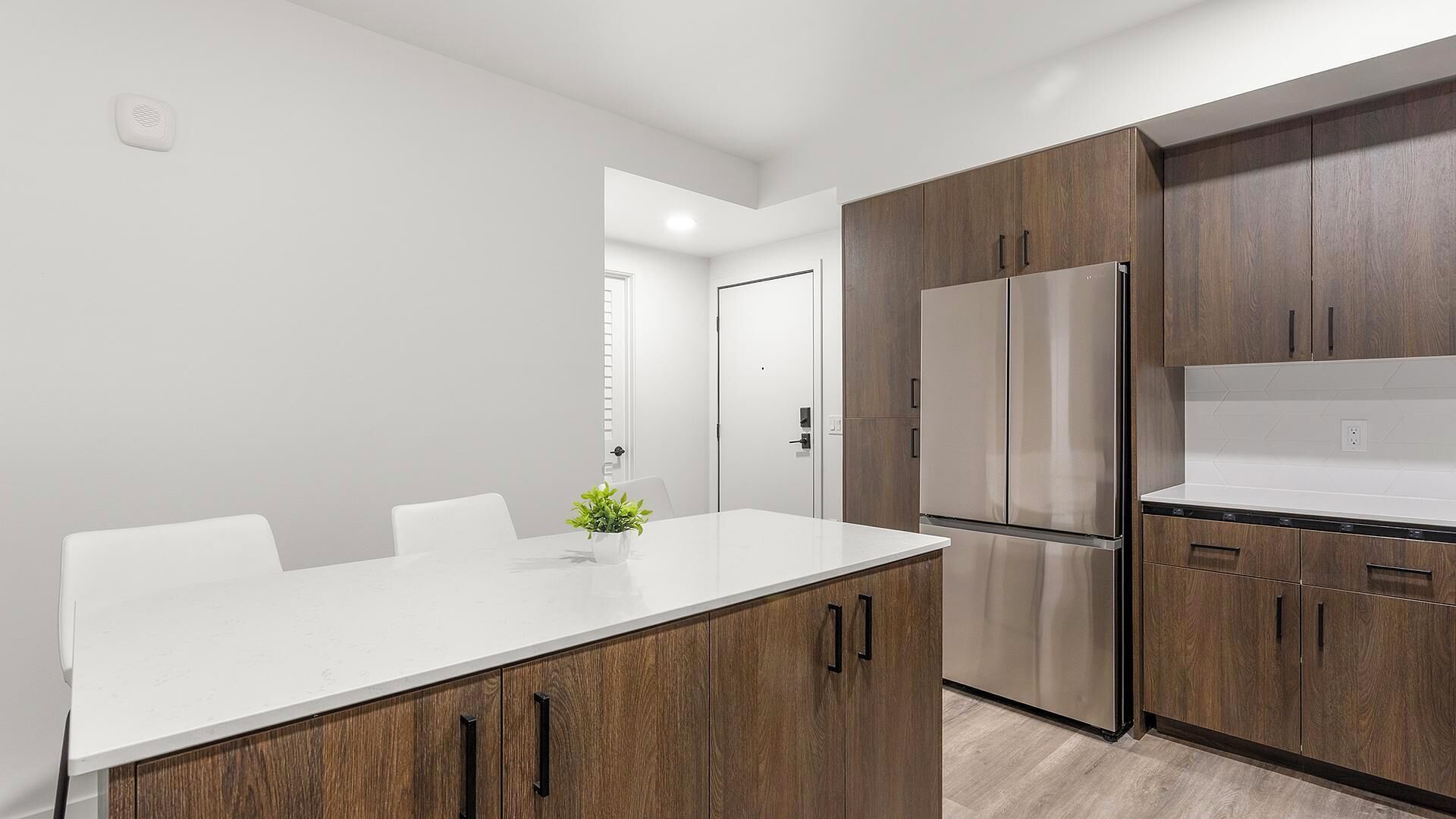 Una cocina moderna con encimera blanca, armarios de madera y electrodomésticos de acero inoxidable.