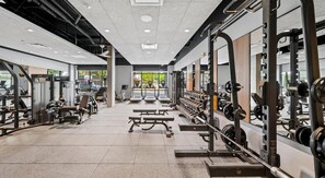 A modern gym with various exercise equipment, including treadmills, weight machines, and free weights. - Landing | Incredible 2BD, Gym (Seattle)