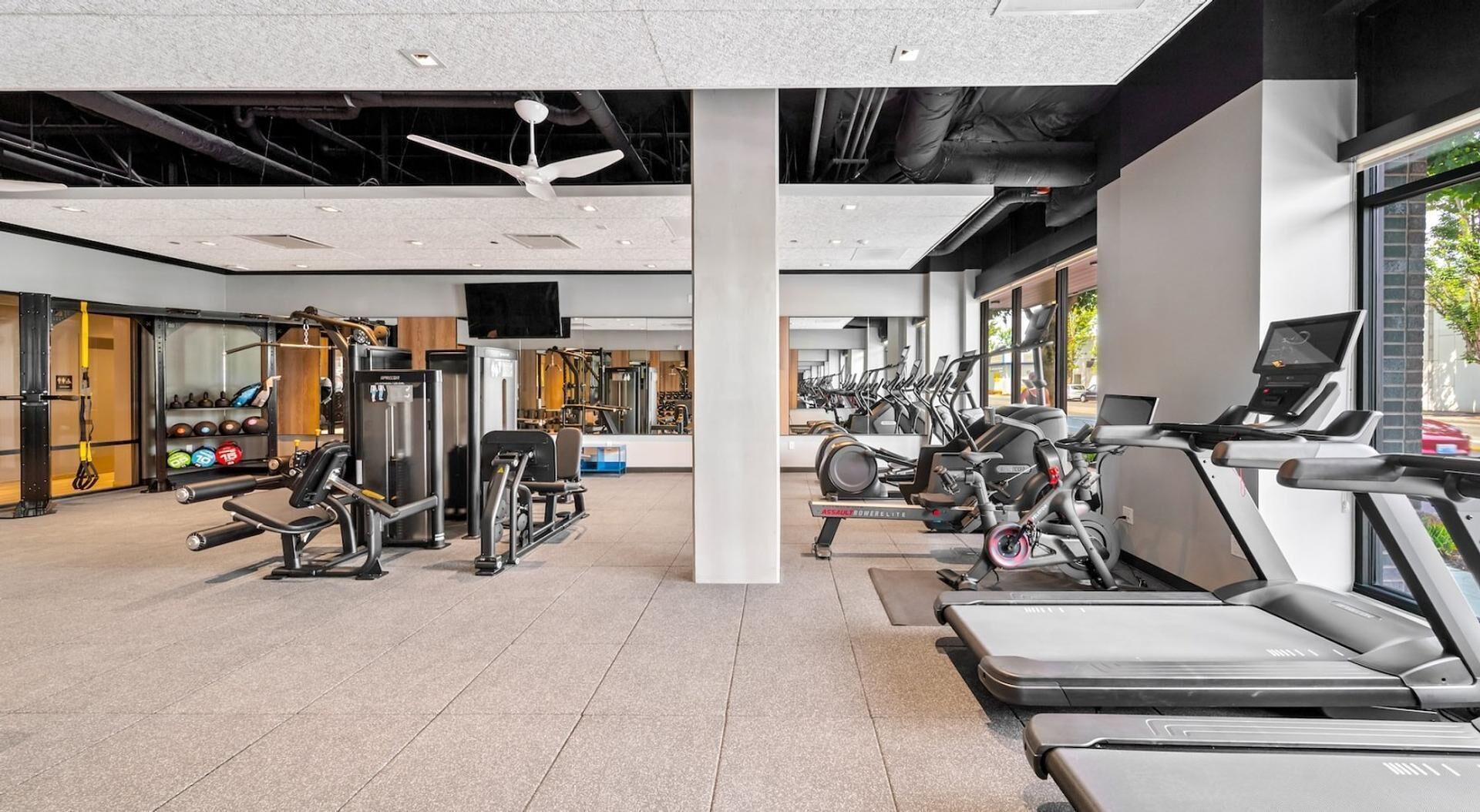 Een moderne sportschool met diverse fitnessapparaten, waaronder loopbanden, hometrainers en krachttrainingsmachines.