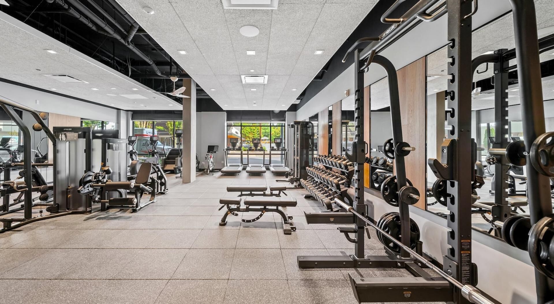Ein modernes Fitnessstudio mit verschiedenen Trainingsgeräten, darunter Laufbänder, Kraftgeräte und Kurzhanteln.