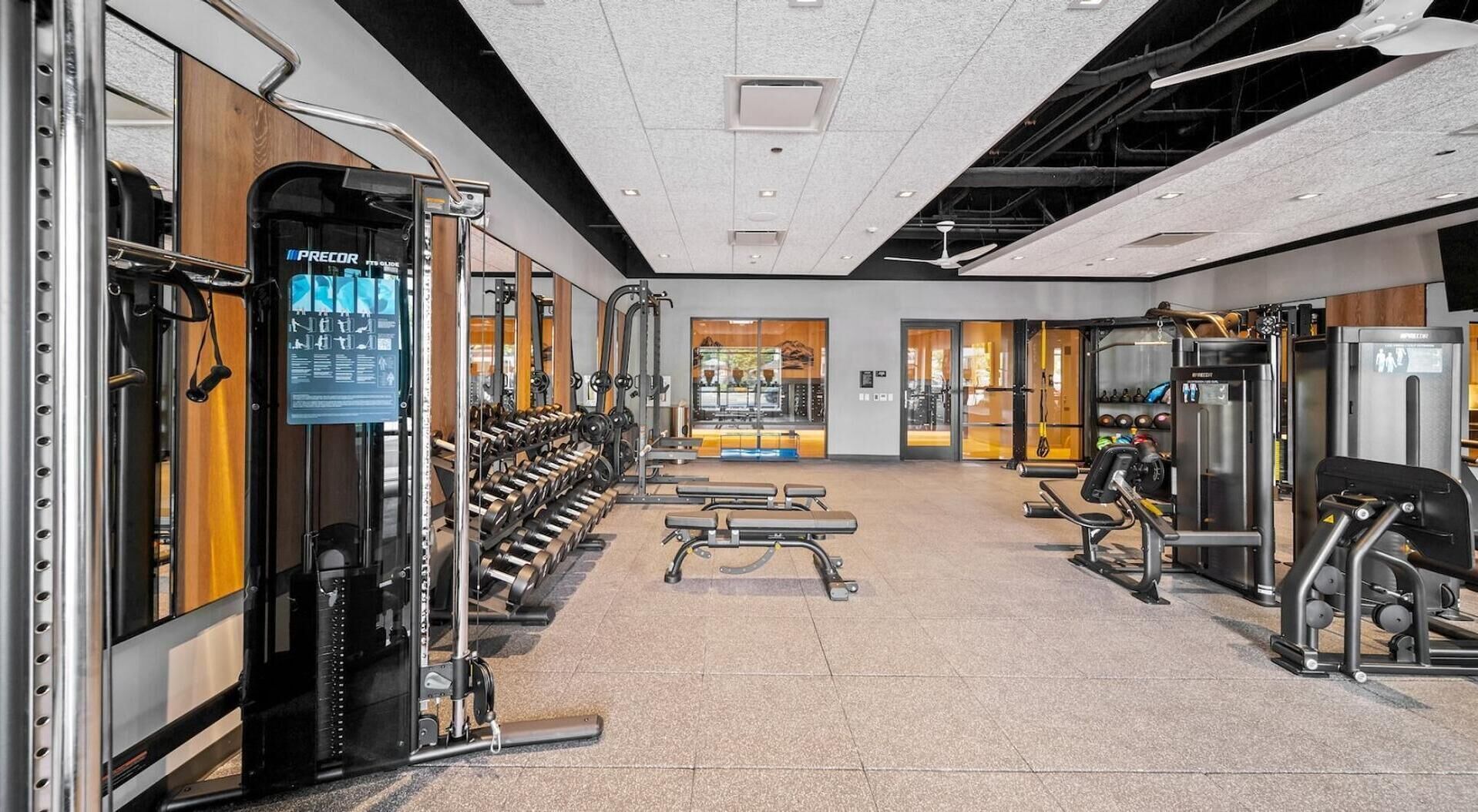 Un gimnasio con diverso equipamiento de ejercicio, bancos y jaulas para pesas.