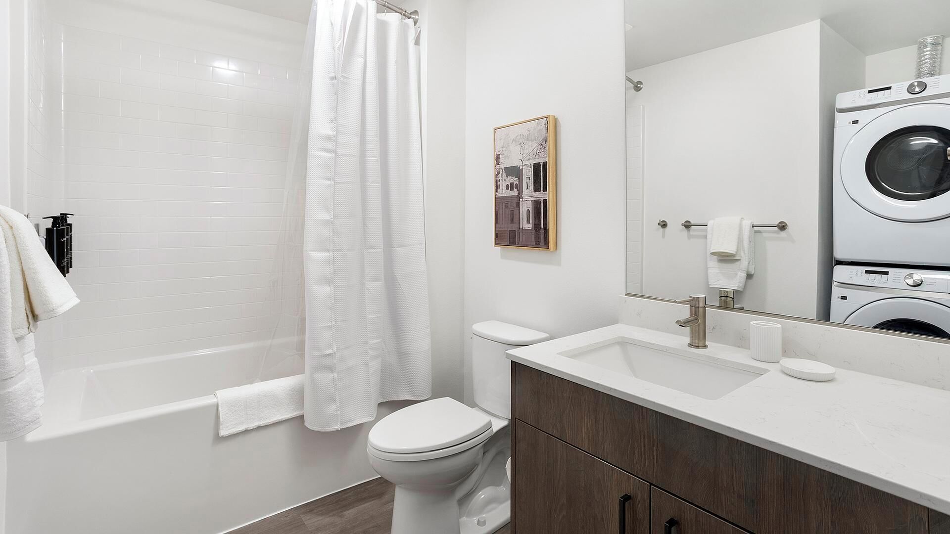 Une salle de bain moderne équipée d’une baignoire, de toilettes et d’un lave-linge.