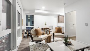 Una sala de estar moderna con comedor, que incluye un sofá, sillas, una mesa de centro y una planta en maceta.