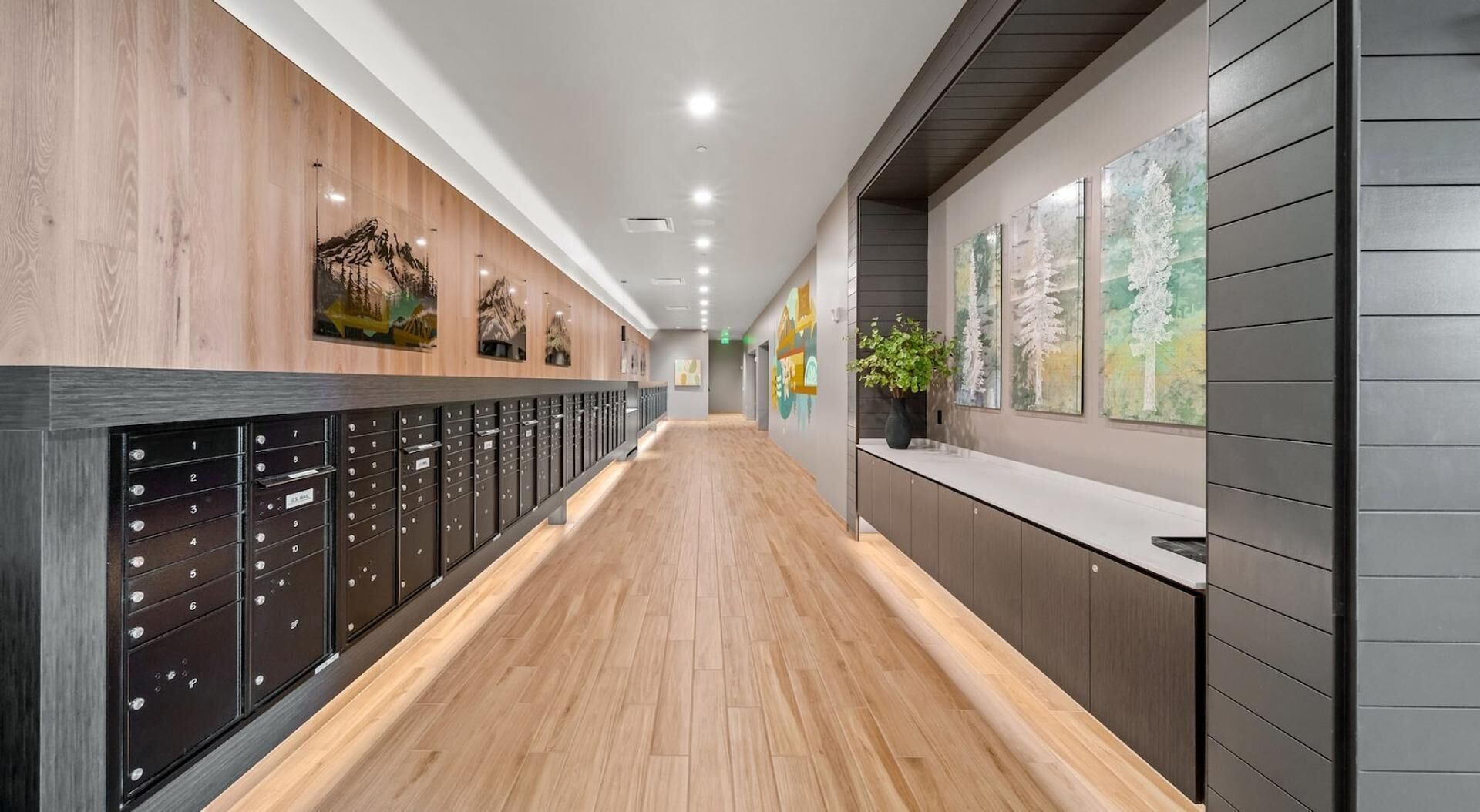 A hallway with lockers, wooden flooring, and artwork on the walls.