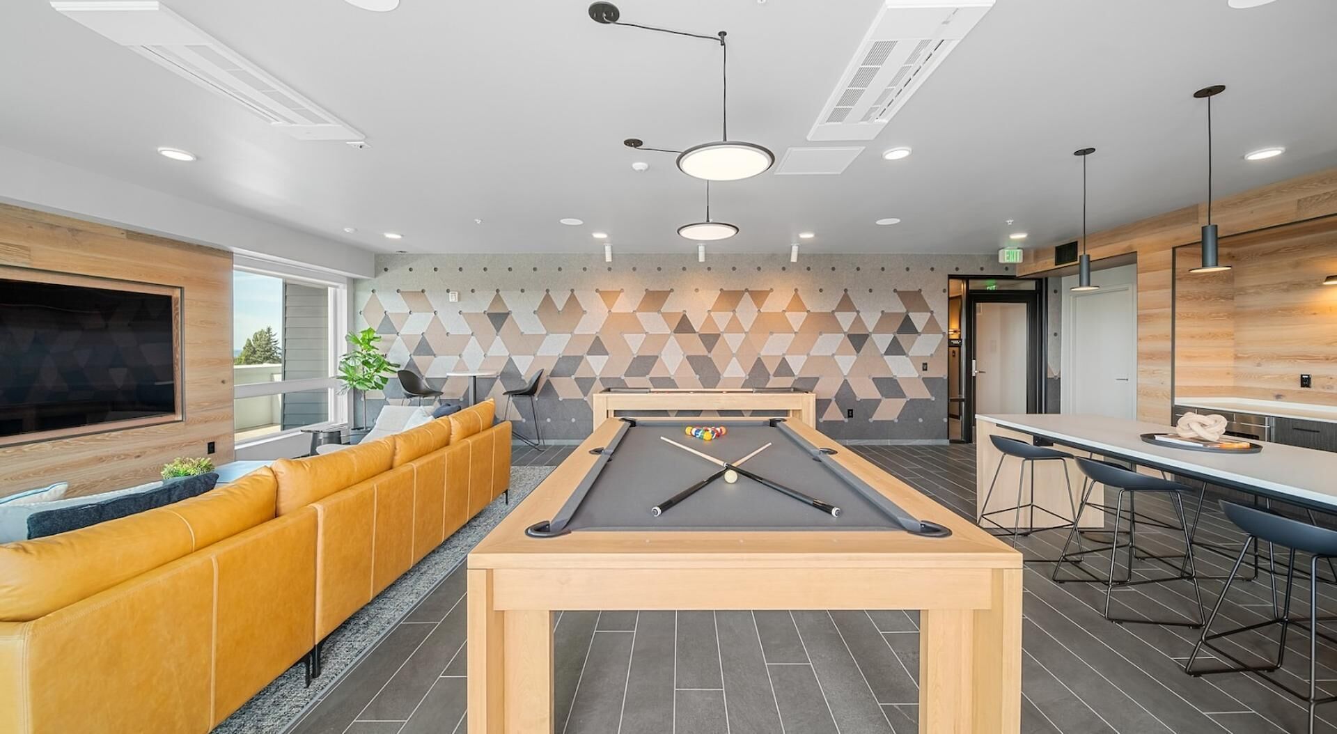 A modern living room with a pool table, a sofa, and a bar area.