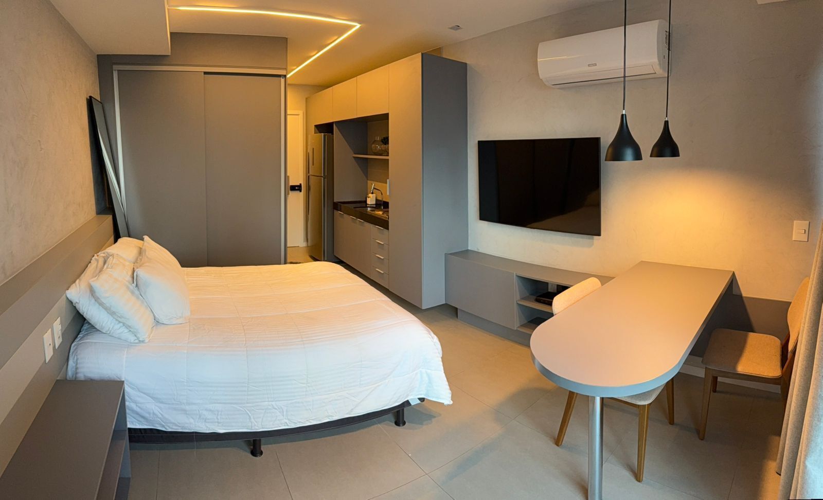 A modern bedroom with a bed, a desk, and a TV.
