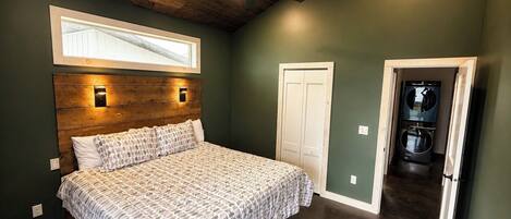 A bedroom with a bed, a ceiling fan, a window, and a door leading to a laundry area.