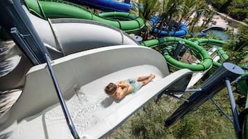 A water slide with a person lying on it, surrounded by green and blue water slides.