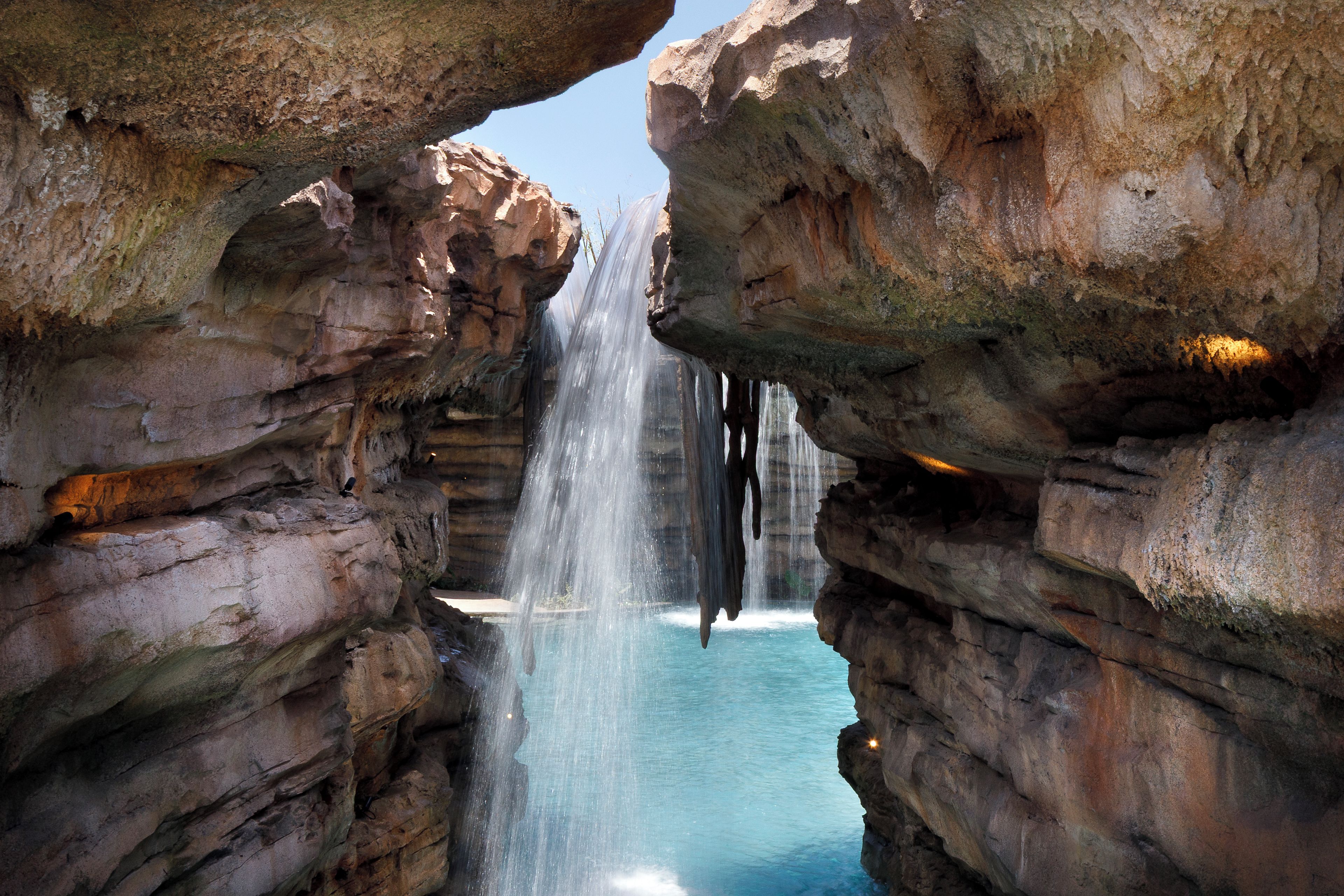 A natural rock formation with a waterfall and a pool of water at the base.