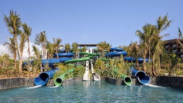Un parc aquatique doté de nombreux toboggans et de plusieurs piscines, le tout entouré de palmiers.