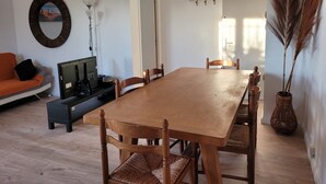 A dining area with a wooden table, chairs, a sofa, and a lamp. - Appart in solar villa and veranda garden in quiet cul-de-sac - 8mn from the sea (Lattes)