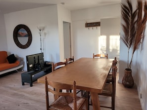 A dining area with a wooden table, chairs, a sofa, and a lamp. - Appart in solar villa and veranda garden in quiet cul-de-sac - 8mn from the sea (Lattes)