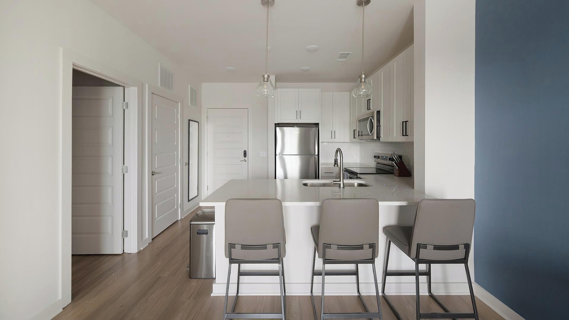 A modern kitchen with a central island, stainless steel appliances, and bar stools.