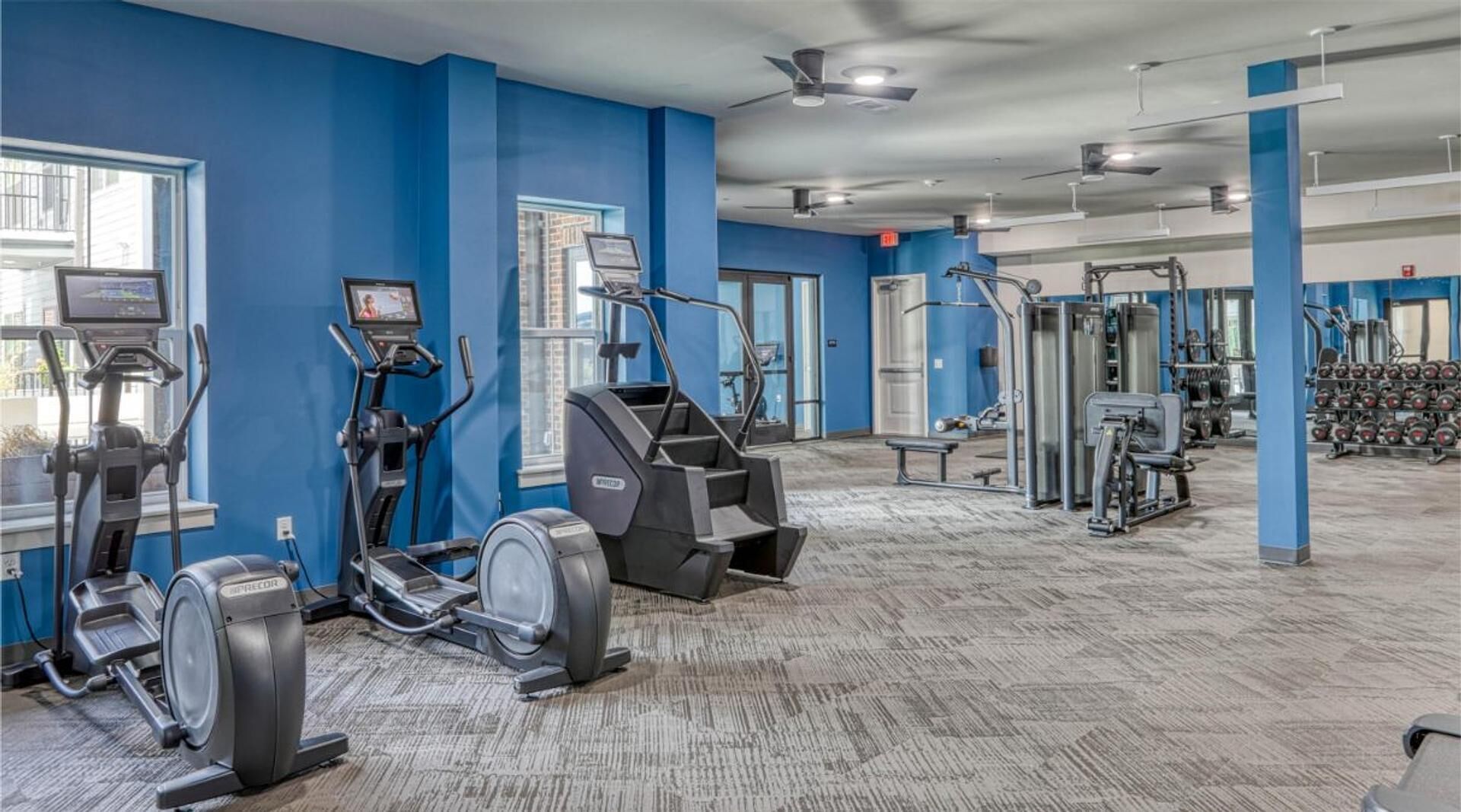Ein Fitnessstudio mit Laufbändern, Crosstrainern und Gewichten.