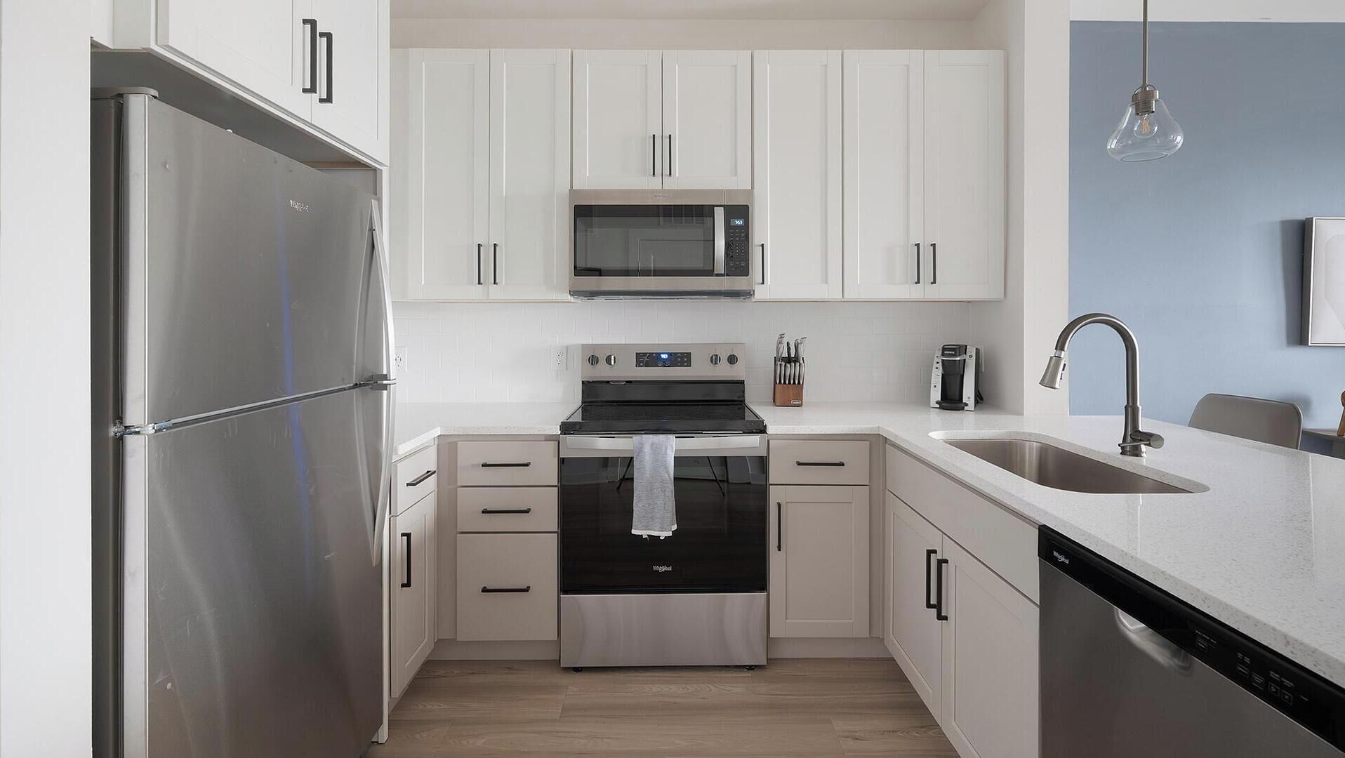 Una cocina moderna con electrodomésticos de acero inoxidable, muebles blancos y lavavajillas.