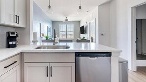 Eine moderne Küche mit Spülmaschine, Kaffeemaschine und großem Fenster.