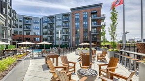 A rooftop patio with outdoor seating, a pool, and a view of the surrounding buildings. - Landing | Spectacular 2BD, Pool, Game Room (Knoxville)