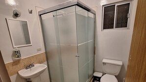 A bathroom with a glass-enclosed shower, a sink, a toilet, and a small window. - Perfect 3-bedroom house in Chihuahua for a relaxing getaway (Chihuahua)