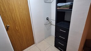 A room with a wooden door, tiled floor, a black wardrobe with drawers, and a metal hanger on the wall. - Perfect 3-bedroom house in Chihuahua for a relaxing getaway (Chihuahua)