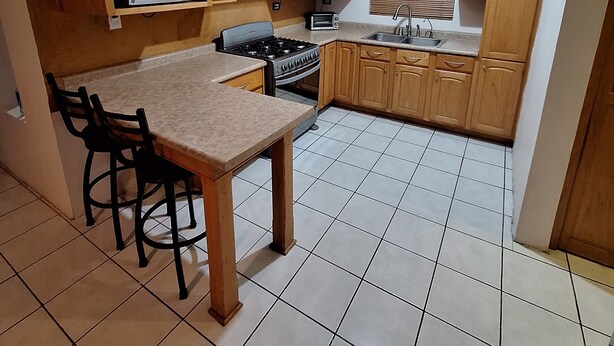 A compact kitchen with wooden cabinets, a microwave, a stove, and a sink. - Perfect 3-bedroom house in Chihuahua for a relaxing getaway (Chihuahua)