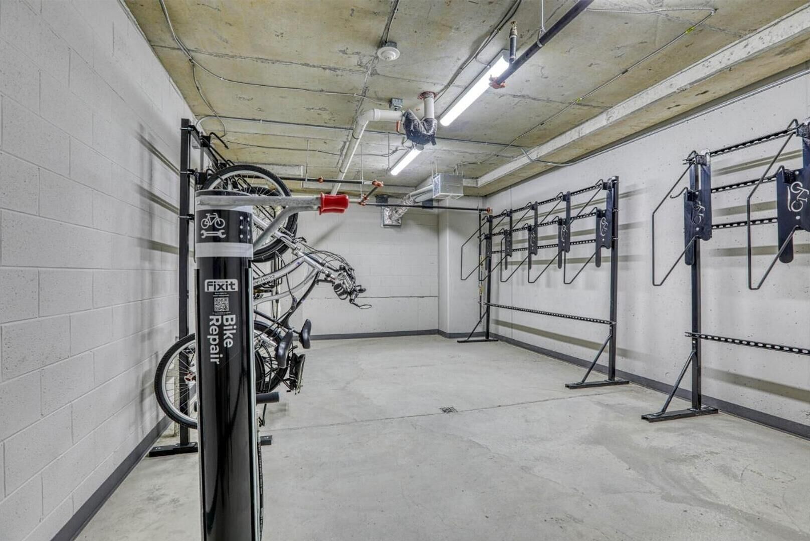 Una stazione di riparazione biciclette con cavalletto, rastrelliera e scaffalatura a soffitto, situata in un ambiente interno pulito.