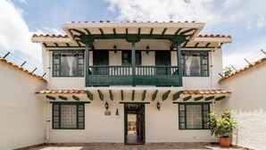 A two-story building with a balcony, a tiled roof, and a courtyard.