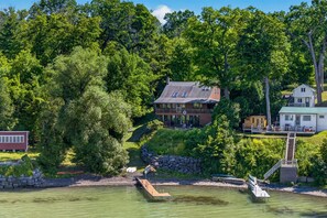 Una propiedad frente al lago con una casa principal, una edificación más pequeña y un muelle.
