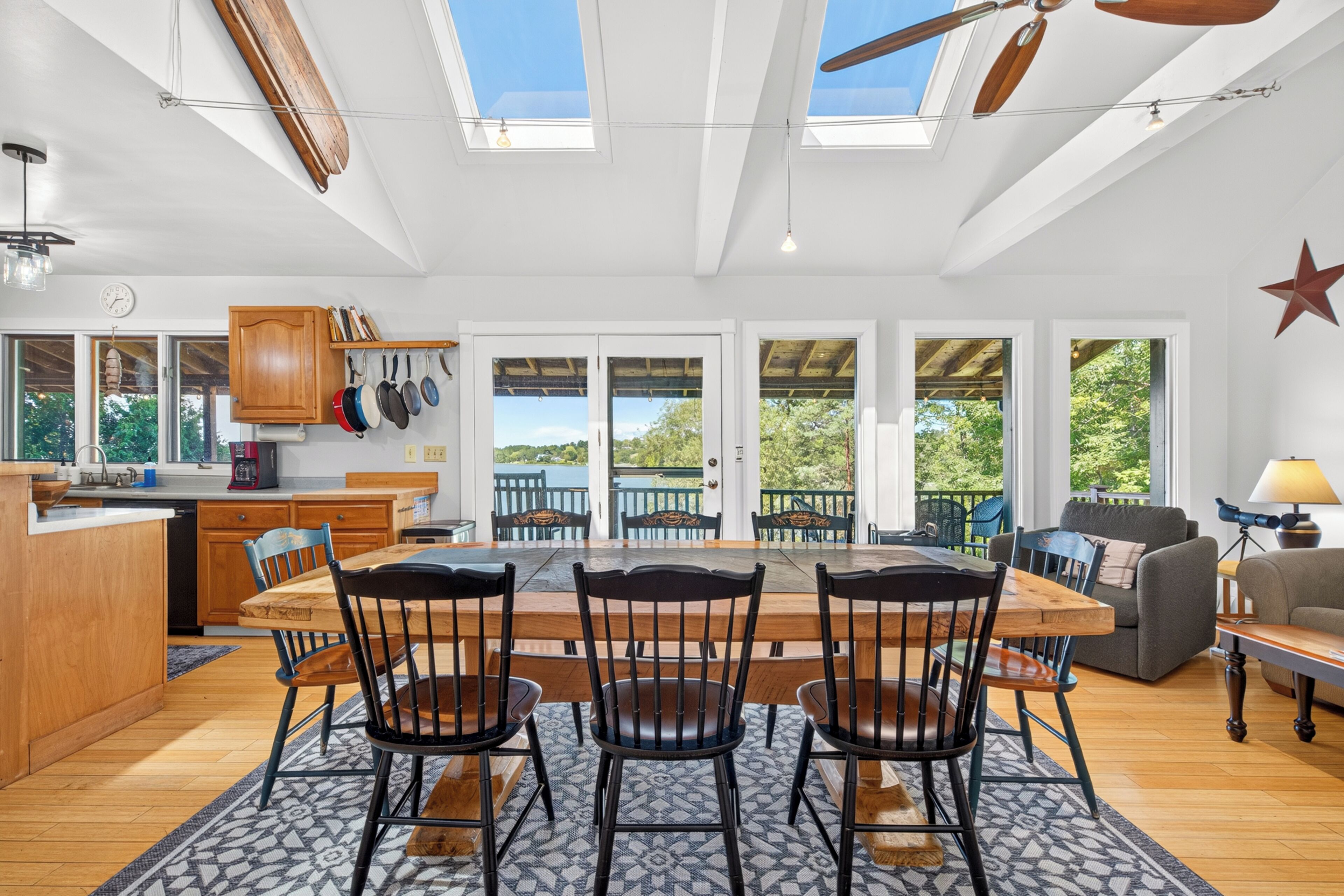 A spacious kitchen with a dining area, large windows, and a ceiling fan.