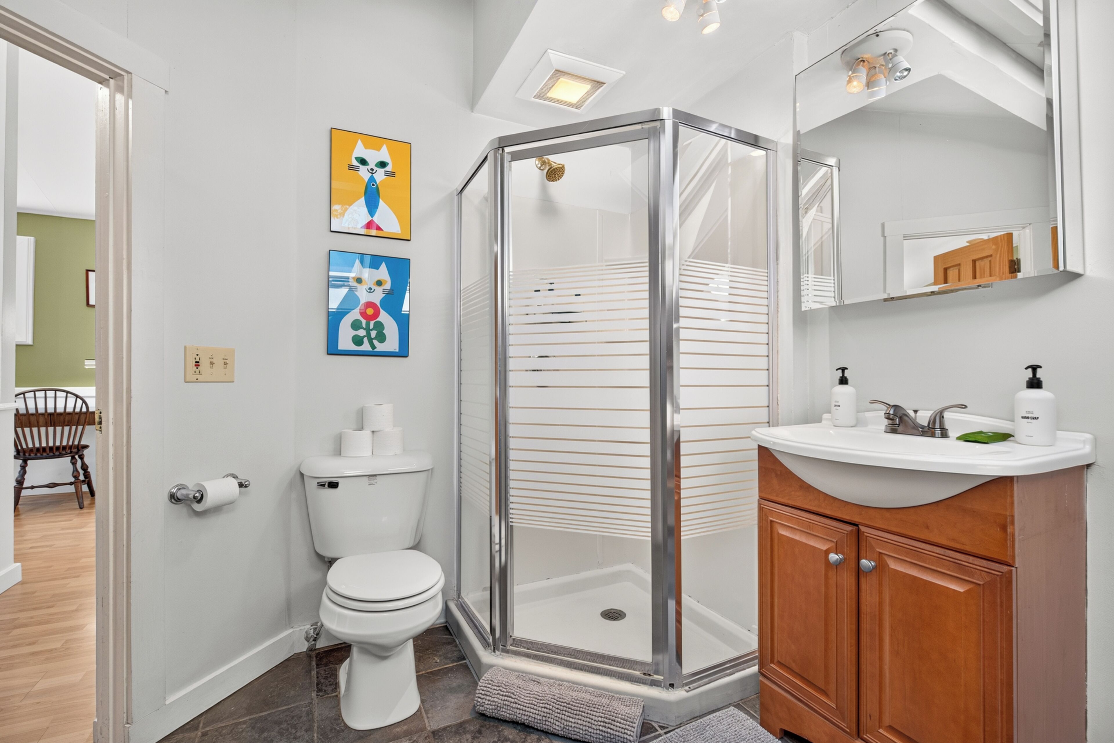A bathroom with a toilet, shower, sink, and cabinet.