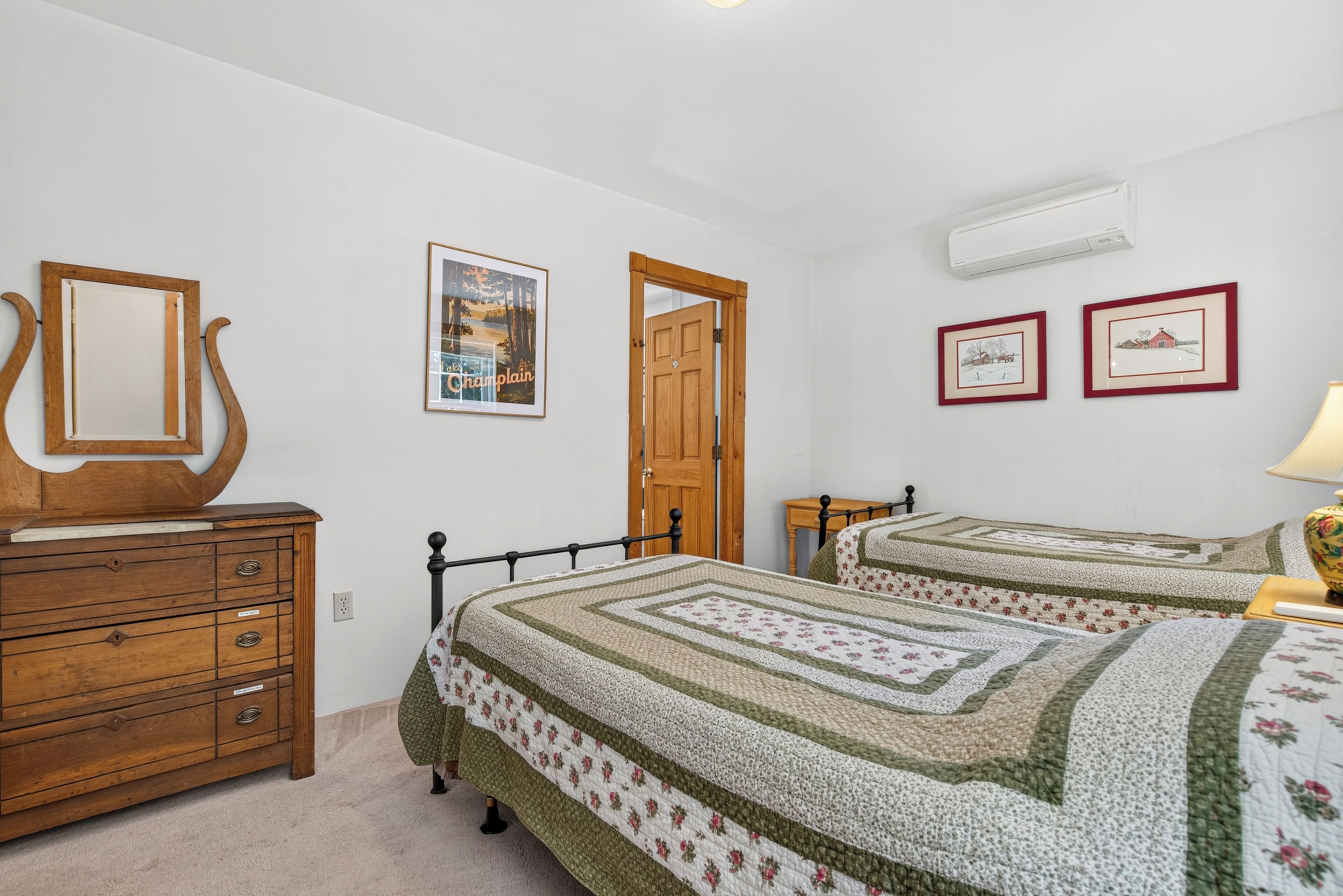 Un dormitorio con dos camas, un aparador, un espejo y cuadros en la pared.