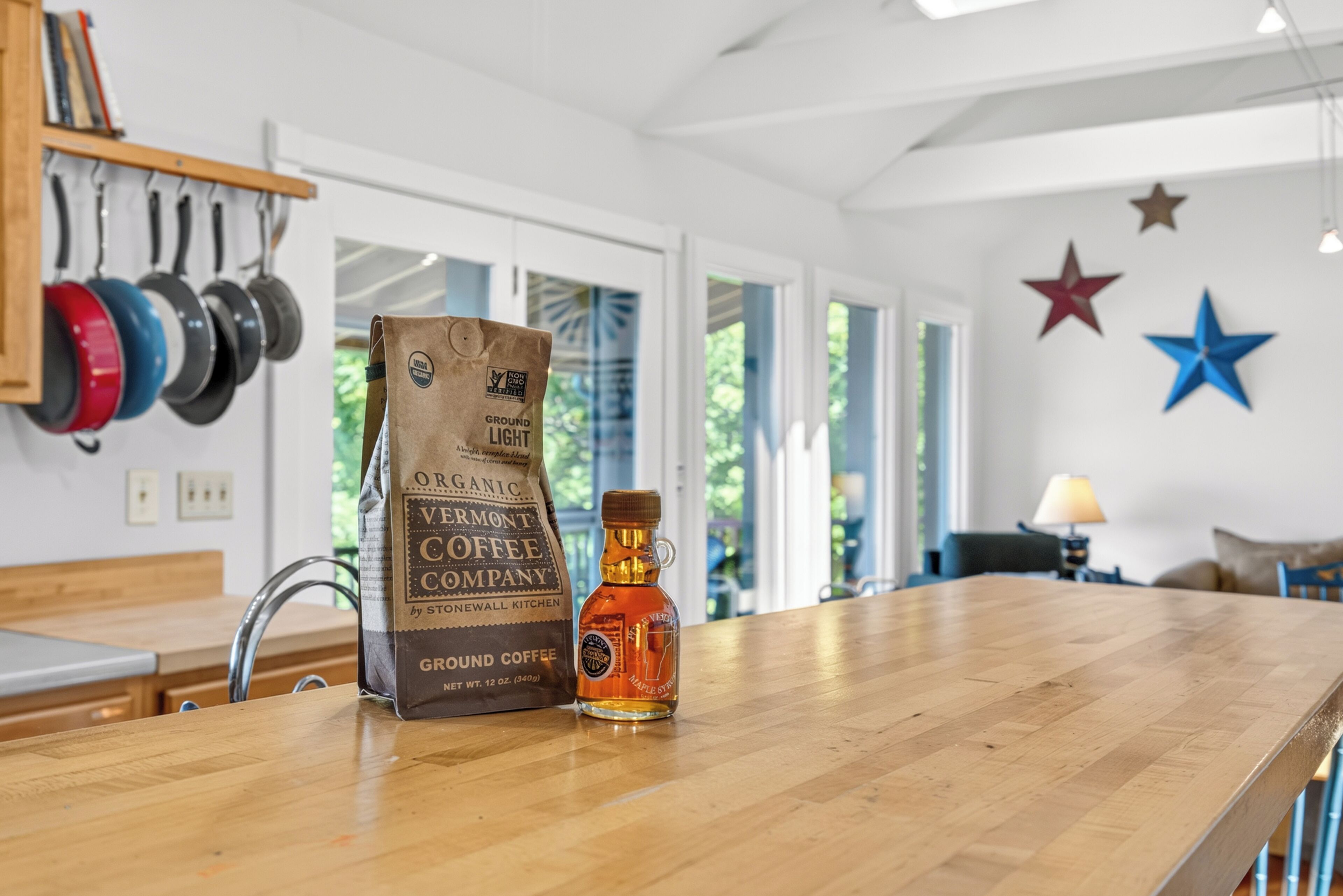 Una encimera de cocina con un paquete de café molido de Vermont Coffee Company y una botella de jarabe de arce.