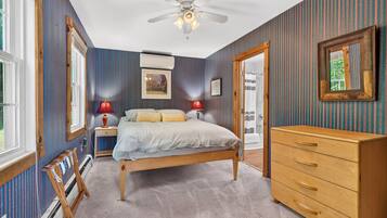A bedroom with a bed, dresser, and a ceiling fan.