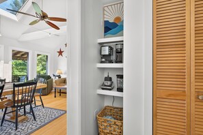 Una cocina moderna con electrodomésticos integrados, un comedor con una mesa y sillas de madera, y un ventilador de techo.