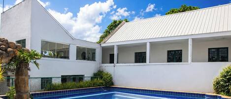 A modern building with a swimming pool, large windows, and a white exterior.