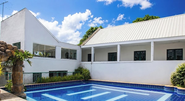 Un bâtiment moderne doté d’une piscine, de grandes fenêtres et d’une façade blanche.