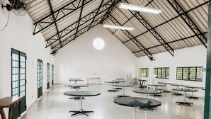 A spacious indoor area with high ceilings, multiple tables, and chairs arranged for dining or meetings. - Chácara 3 Poderes Piscina - 60 pessoas (Guararema)