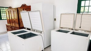 A room with two white refrigerators, wooden cabinets, and a window with green frames. - Chácara 3 Poderes Piscina - 60 pessoas (Guararema)