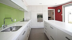 A modern kitchen with white cabinets, a stainless steel sink, and a green backsplash.