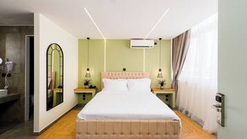 A modern bedroom with a large bed, bedside tables, a mirror, and an air conditioning unit.