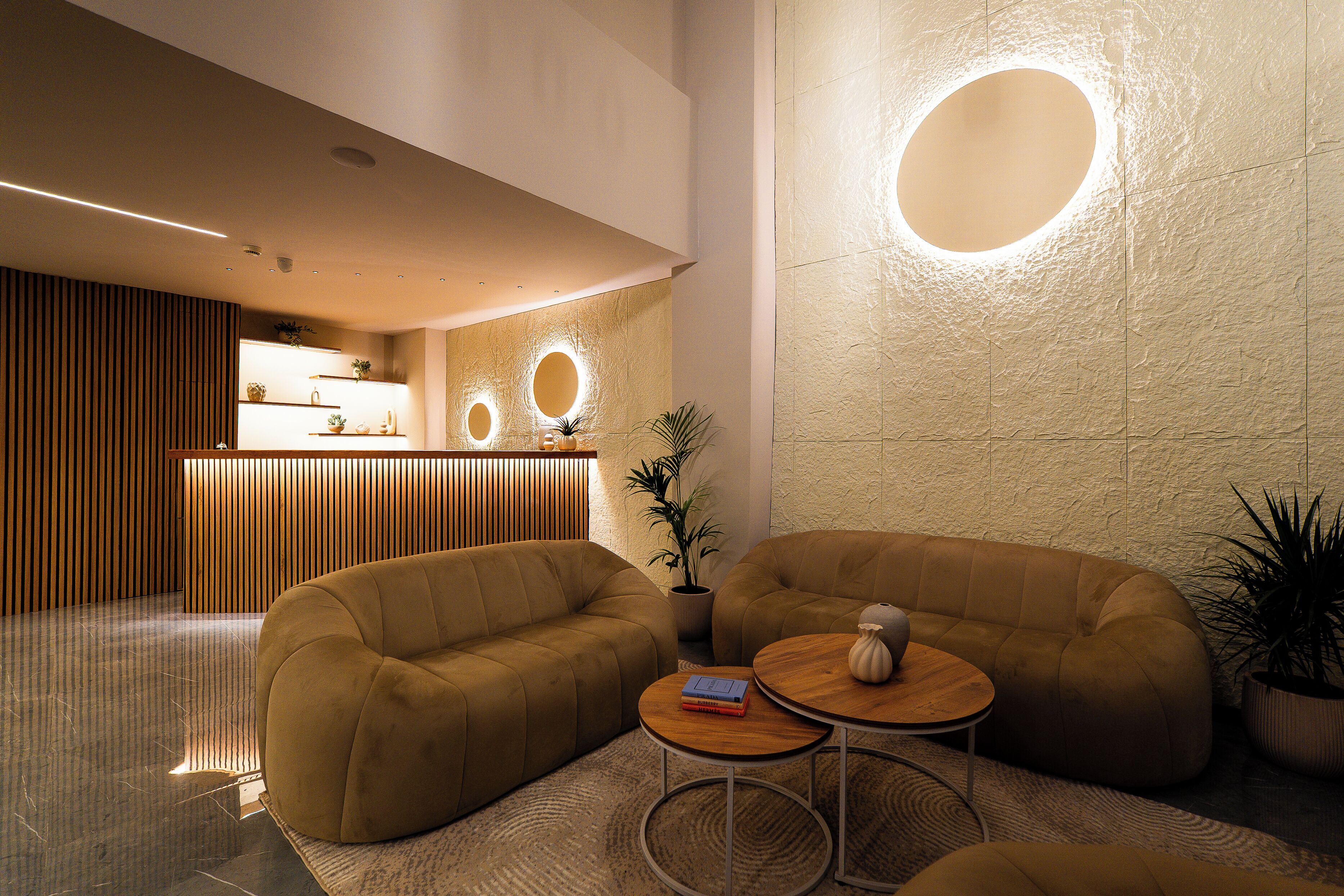 A modern lobby with a reception desk, sofas, and a coffee table.
