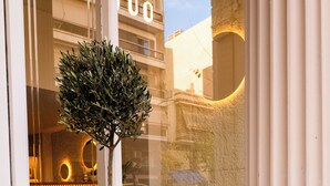 A potted tree in front of a building with a large window.