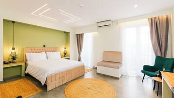 Un dormitorio moderno con una cama grande, una pared de acento verde, un tapete redondo tejido y un sillón verde.