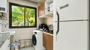Una cucina compatta con lavatrice, forno a microonde e frigorifero.
