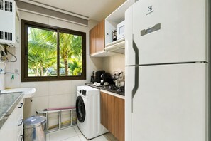 Une cuisine compacte équipée d’un lave-linge, d’un four à micro-ondes et d’un réfrigérateur.